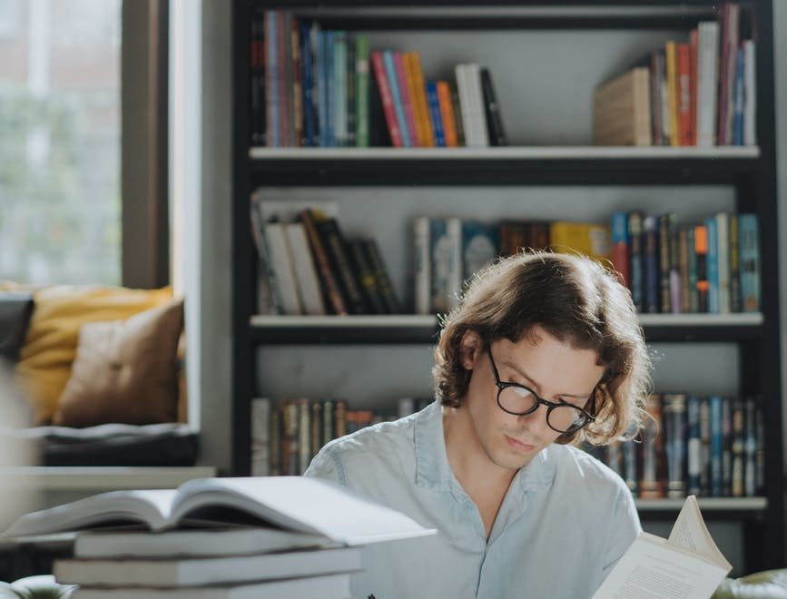 man in white dress shirt reading book