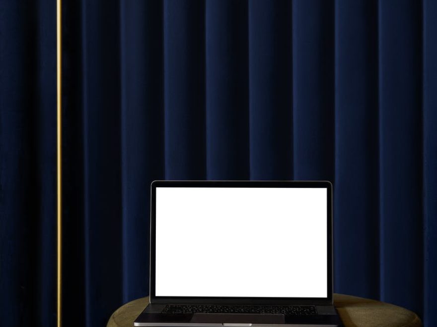 netbook on pouf near curtain in room