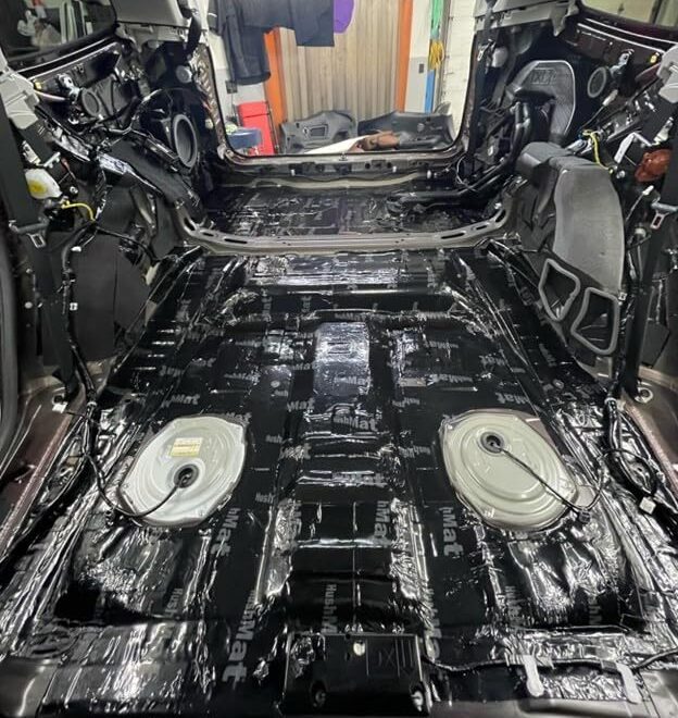 HushMat Bulk Kit black foil sound deadening sheets installed across stripped vehicle interior floor
