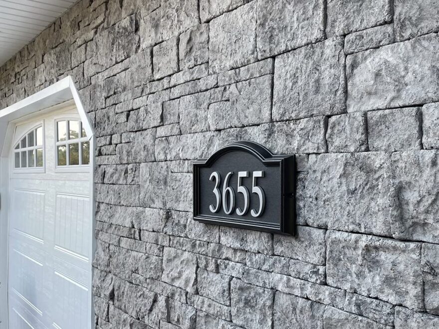 Capital Sky NonRated Flat Stone Veneer in Phantom Shadow, gray mortarless stone wall beside garage.